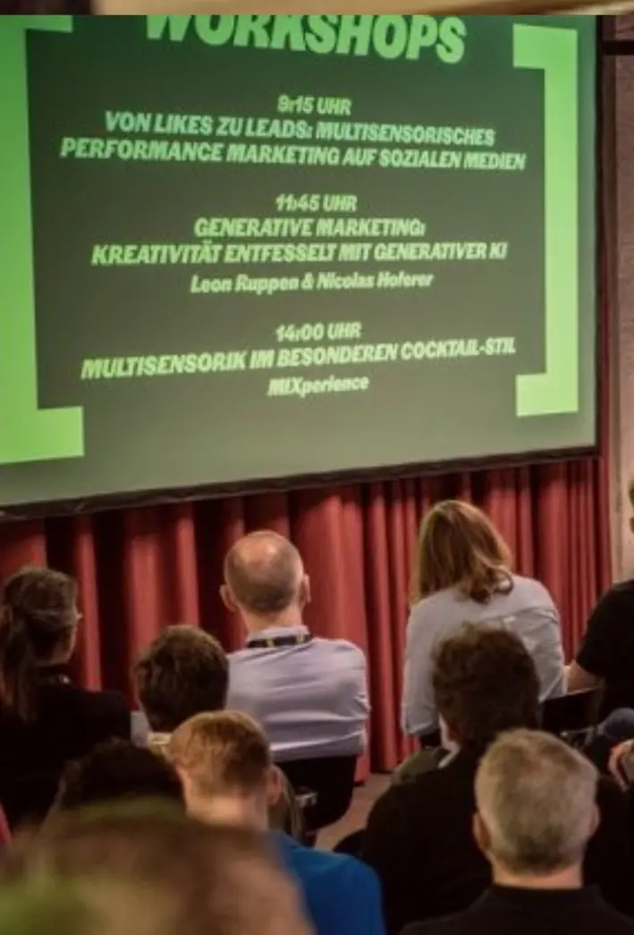 Pubblico nel Papiersaal davanti a uno schermo con il programma dei workshop della SENS7 2026